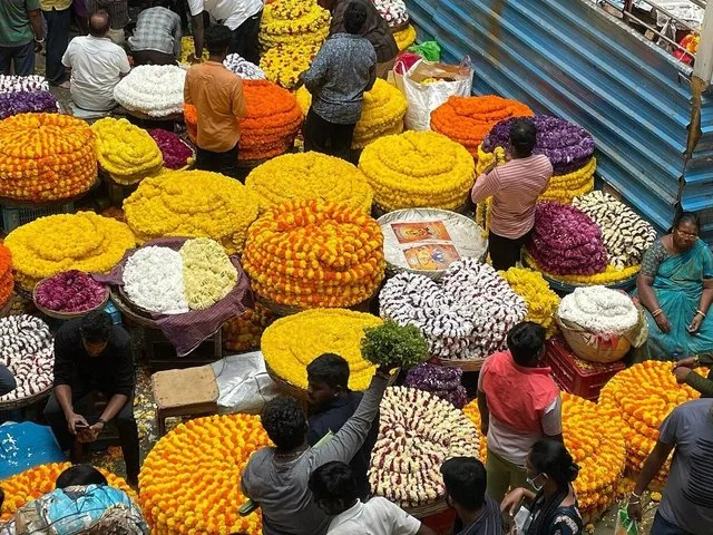 Menschen zwischen großen Körben mit orangen, gelben und weißen Blumen