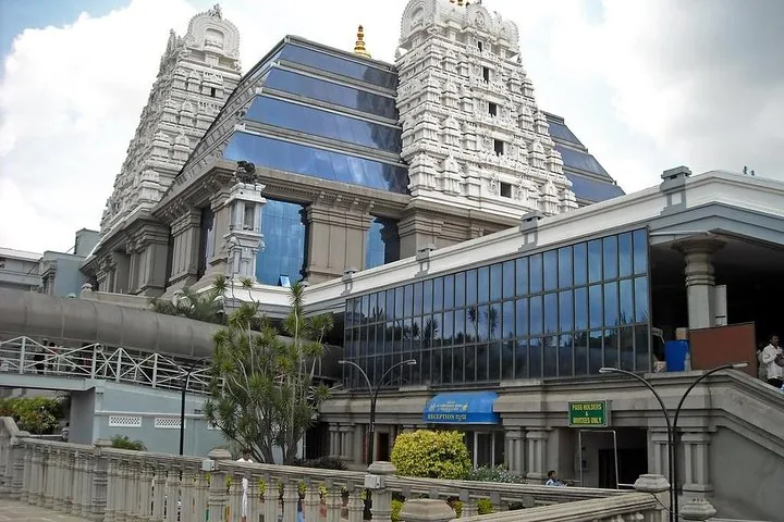 Modern blue glass building attached to a traditional white temple